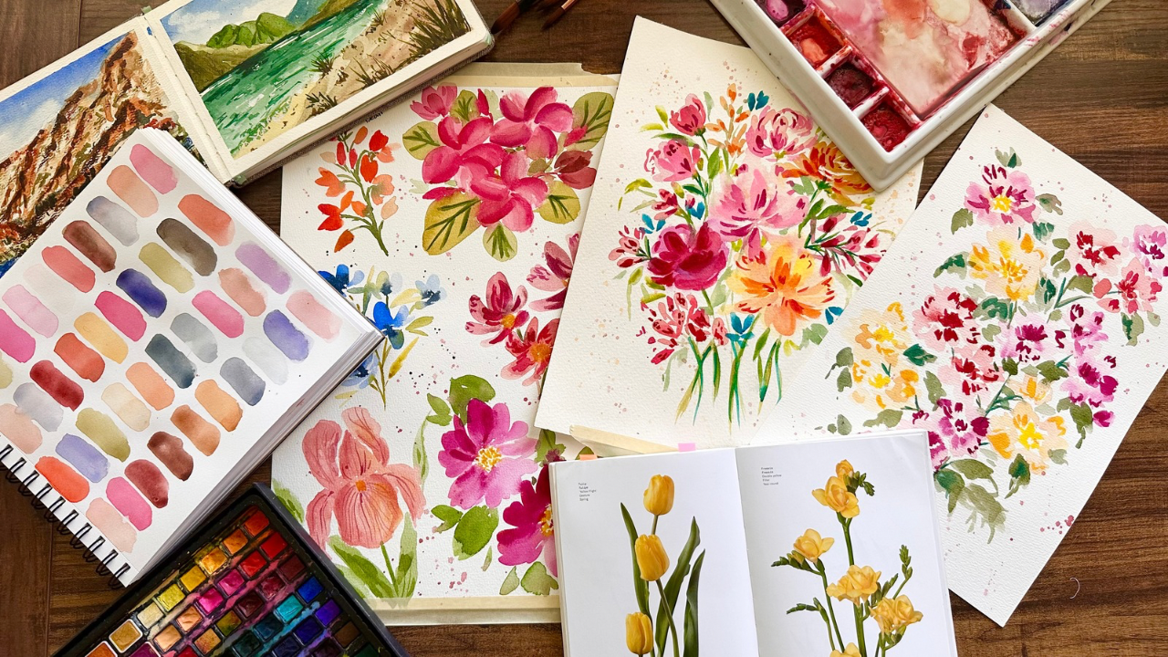 Watercolor flower paintings and paint palette on art desk