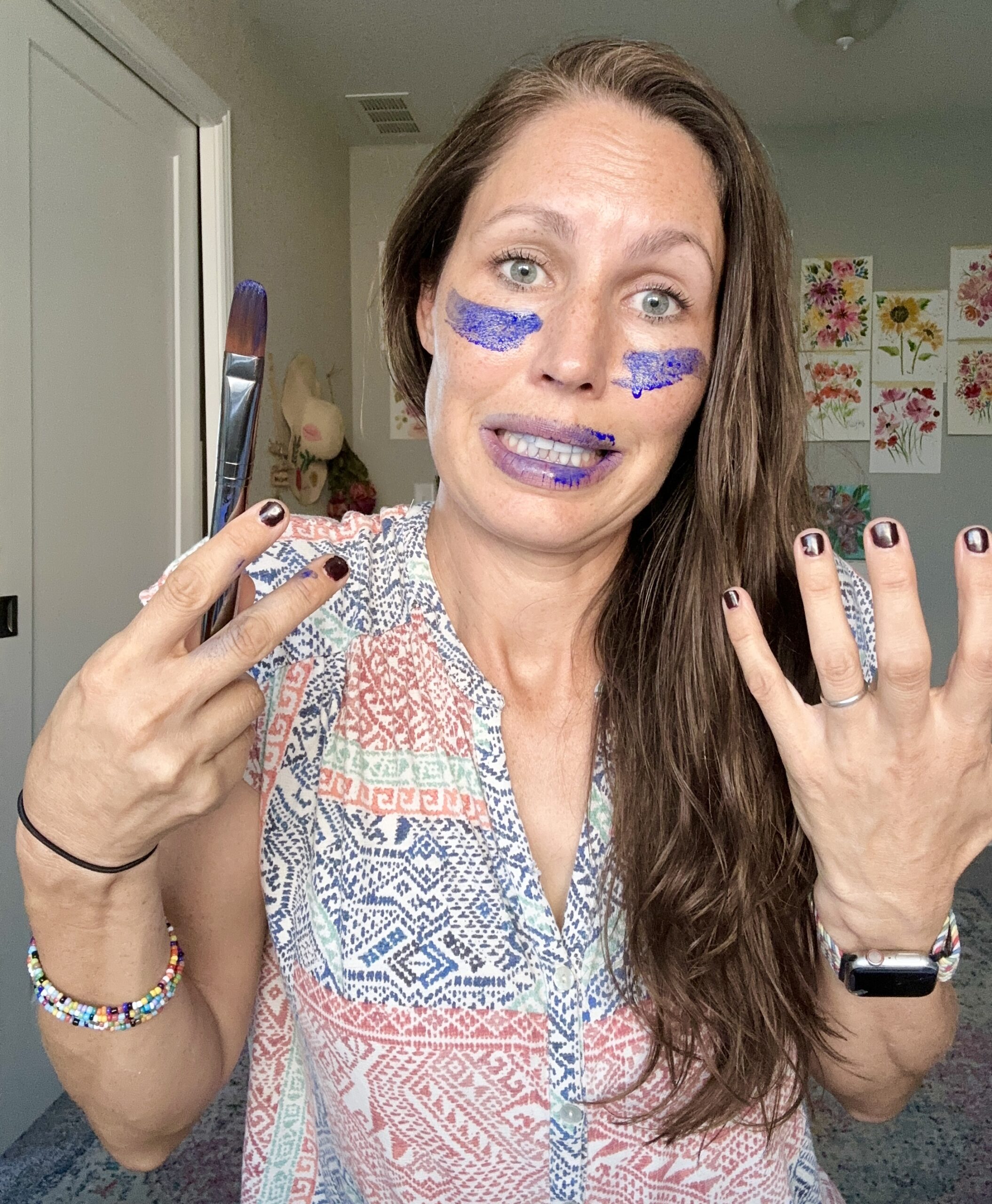 woman with a painted face putting up her hands and making a funny face