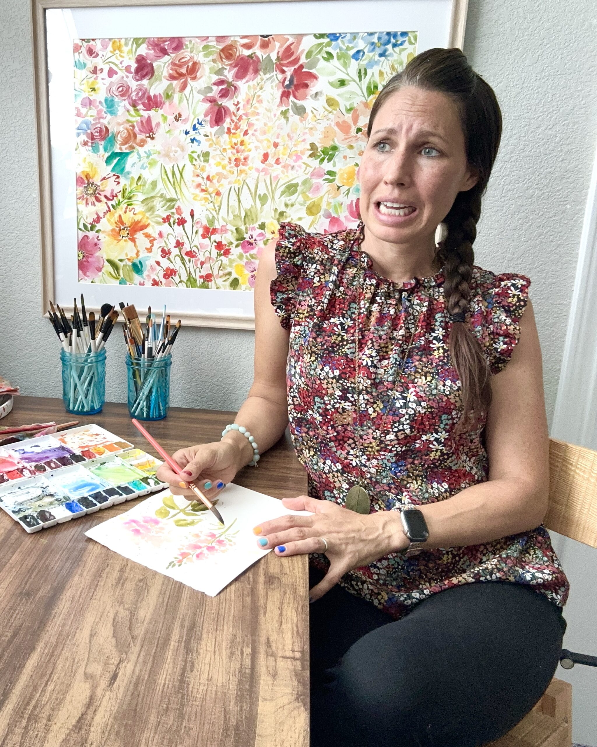 Woman with worried face painting a watercolor flower at art desk